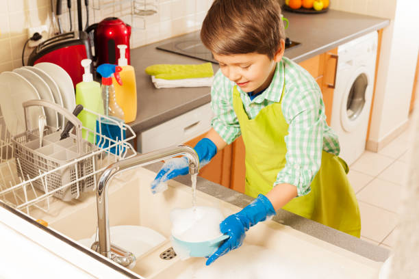 istock Nice boy wash dish in sink under water from tap 658669646