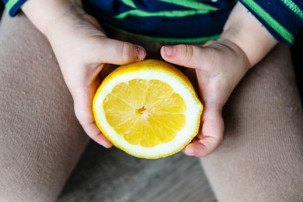 istock beautiful fresh yellow lemon in child hands 658675796