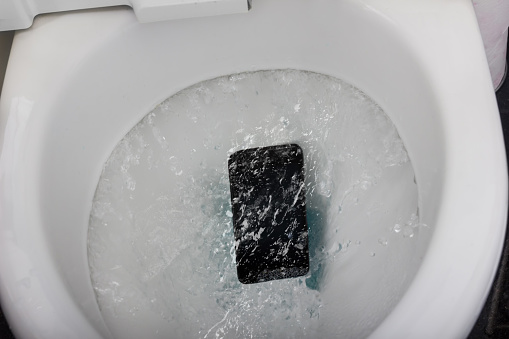 black mobile phone falling into toilet flushing