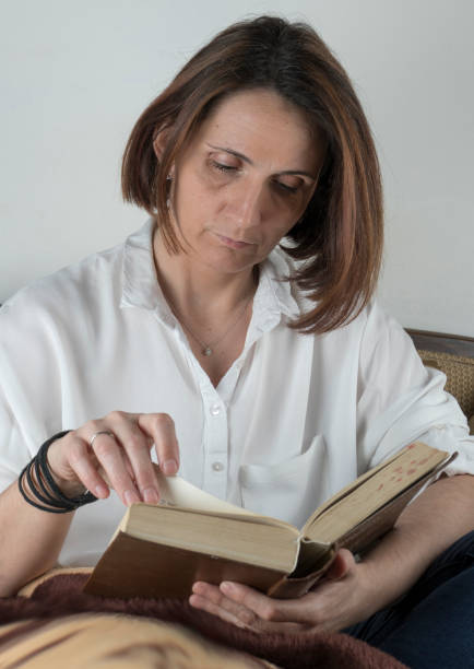 istock Young woman reading a book on a couch 658688556