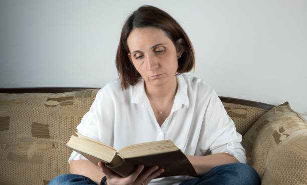 istock Young woman reading a book on a couch 658688702