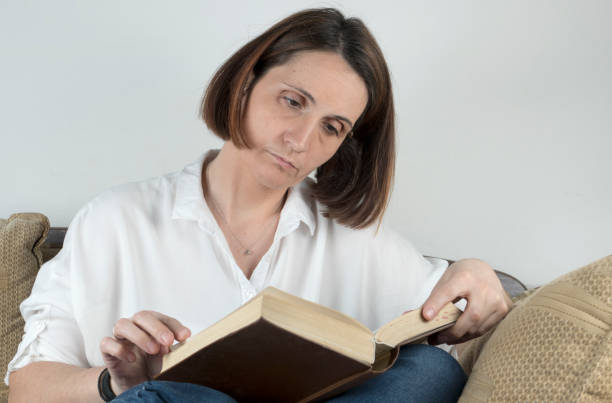 istock Young woman reading a book on a couch 658688774