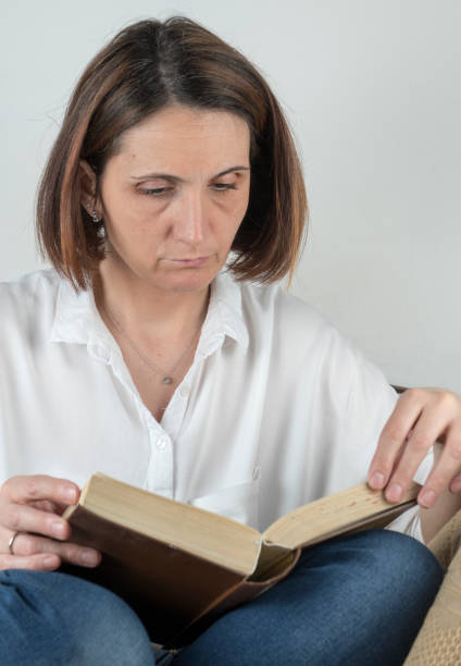 istock Young woman reading a book on a couch 658688780