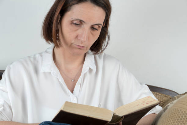 istock Young woman reading a book on a couch 658688844