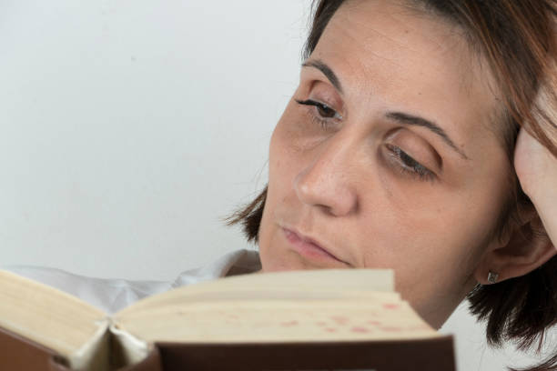 istock Young woman reading a book on a couch 658689090