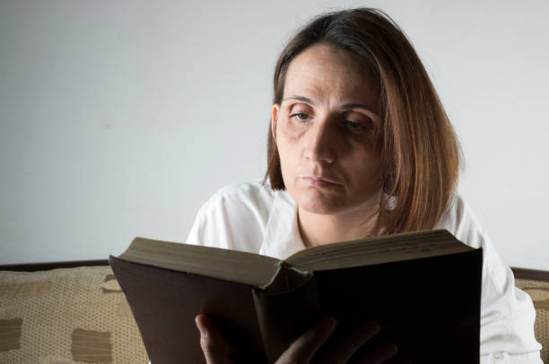 istock Young woman reading a book on a couch 658689254