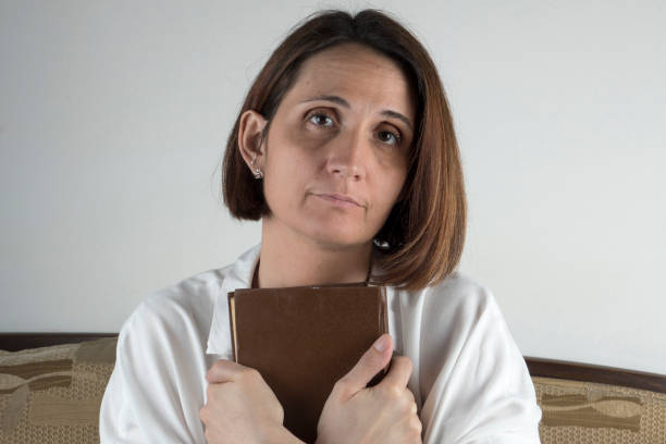 istock Young woman holding a book on a couch 658689302