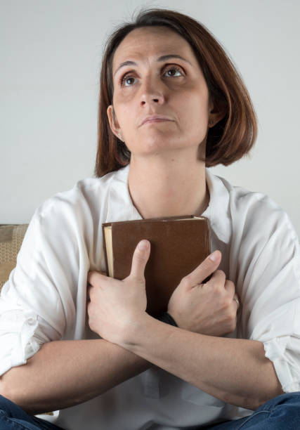 istock Young woman holding a book on a couch 658689470