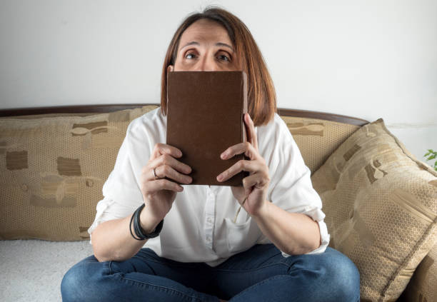 istock Young woman holding a book on a couch 658689654