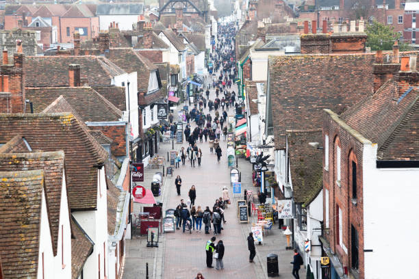 elevated view medieval street with tourists and locals in Canterbury Kent England A cold winter day in famous tourist destination Canterbury in England. The city centre is crowded with tourists and locals despite the chilly weather. The medieval architecture and houses are much in evidence from the elevated viewpoint. Pubs and fast-food restaurants line the historic main street of Canterbury, Kent England. high street stock pictures, royalty-free photos & images
