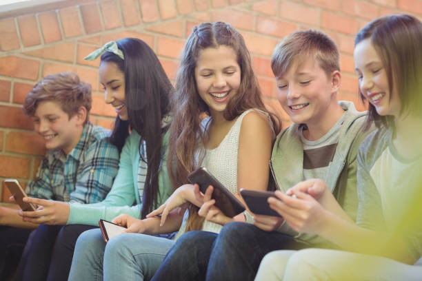 istock Group of smiling school friends sitting on staircase using mobile phone 658702370