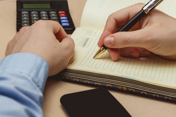 istock Close up of casual man writing on paper notebook or old diary 658724180