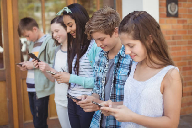 istock Group of smiling school friends using mobile phone in corridor 658734580