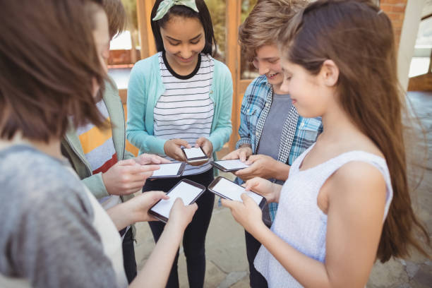 istock Smiling school students standing in circle and using mobile phone 658735416