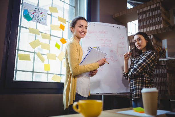istock Confident female colleagues standing by whiteboard 658747928