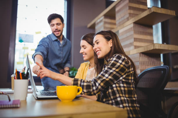 istock Coworkers smiling while pointing at laptop on desk 658789638