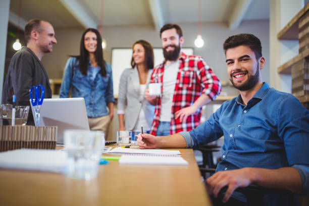 istock Confident creative businessman with colleagues standing by table 658800342