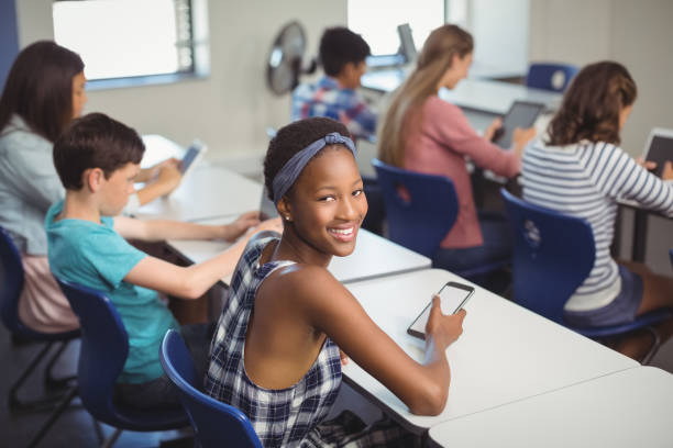 student holding mobile phone in classroom - homework teenager mobile phone school imagens e fotografias de stock