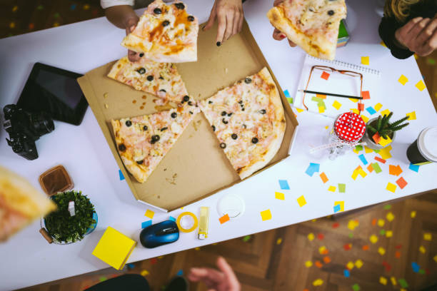 Celebrating Business Success At Pizza Party Everyone's Grabbing Their Slice Of Pizza At Office Party office fun business adhesive note stock pictures, royalty-free photos & images