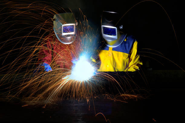 istock Industrial worker welding metal with many sharp sparks and worker during use electric wheel grinding 658826620