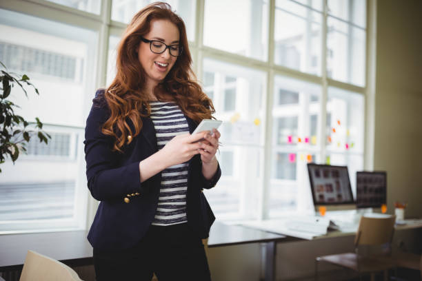 istock Businesswoman using phone at creative office 658826754
