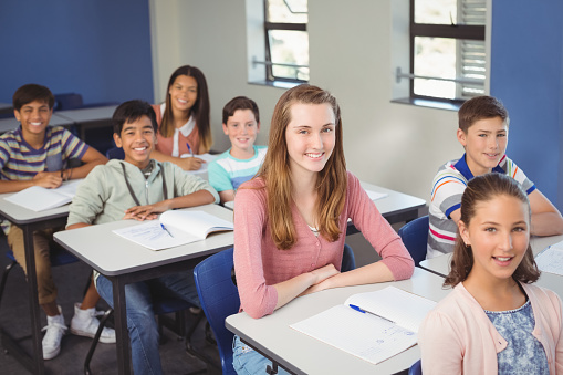 Portrait of smiling school kids sitting in classroom at school