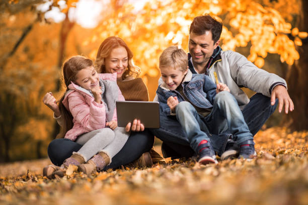 istock Happy family using touchpad while relaxing in autumn day. 658838932