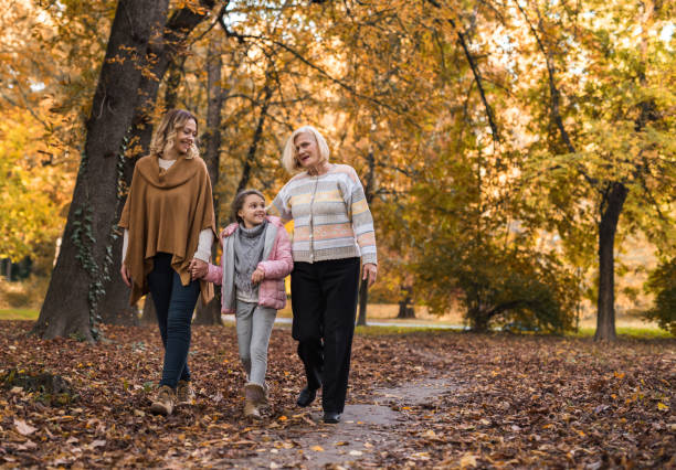 girl walking in autumn day with her mother and grandmother. - grandmother senior adult child multi generation family imagens e fotografias de stock