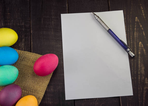 istock Easter eggs with blank paper and pen on wooden table . Happy Easter 658839962