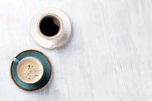 Coffee cups on wooden kitchen table. Top view with copyspace for your text