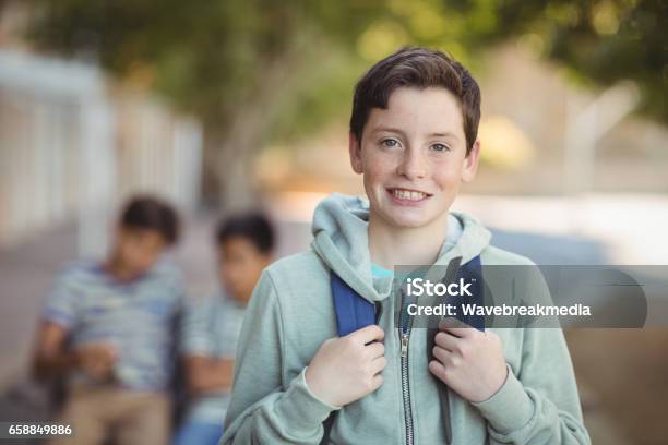 Smiling Schoolboy Standing With Schoolbag In Campus Stock Photo - Download Image Now