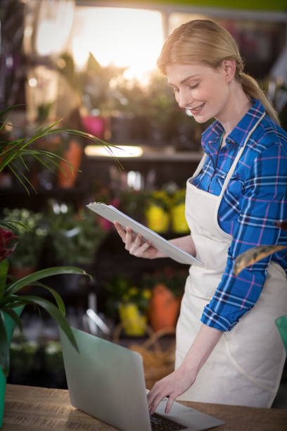 istock Female florist using laptop while holding clipboard 658855528