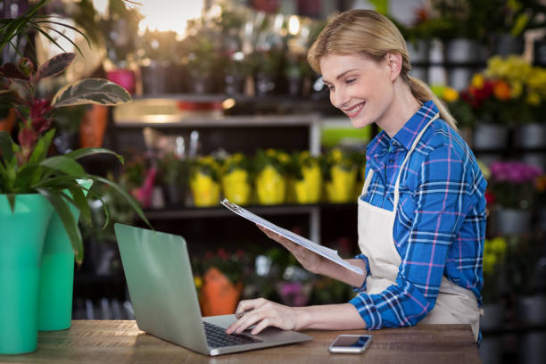 istock Female florist using laptop while holding clipboard 658858002