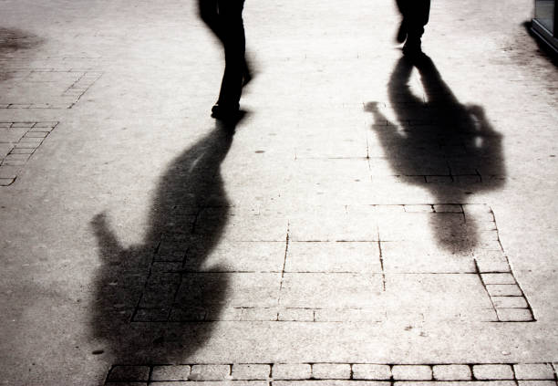 shadow of a man on patterened sidewalk - shadow focus on shadow people men imagens e fotografias de stock