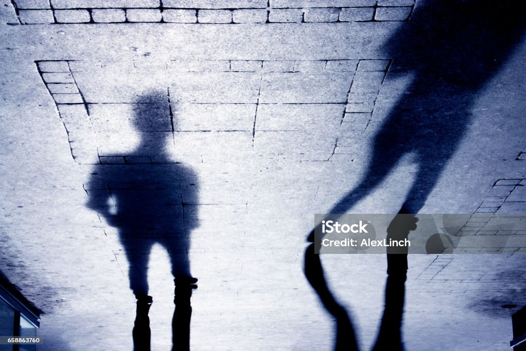 Shadow of a man on patterened sidewalk Upside down shadow of two person on pattered sidewalk, in black and white Sexual Assault Stock Photo