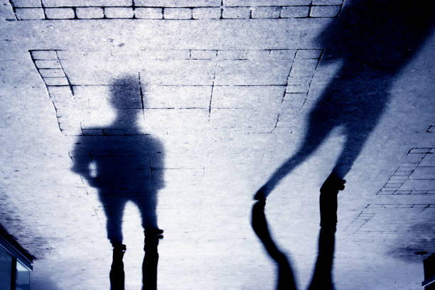 Shadow of a man on patterened sidewalk stock photo