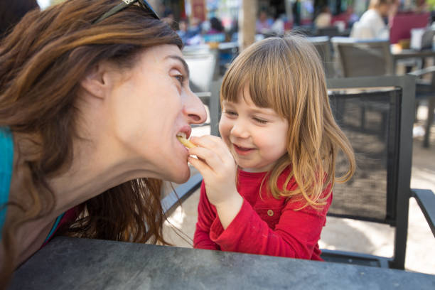 istock child feeding mother with cheese puff in exterior bar 658864238