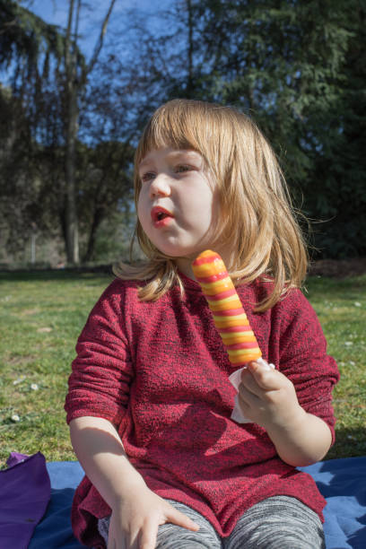istock child with orange and red ice lolly in park 658864302