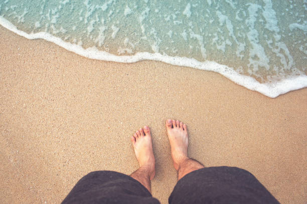 istock Naked feet and sea wave on a sand beach 658876962