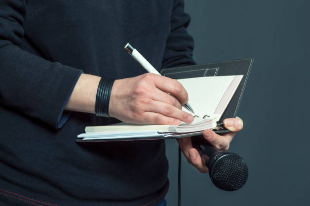 Journalist at press conference, writing notes, holding microphone. stock photo