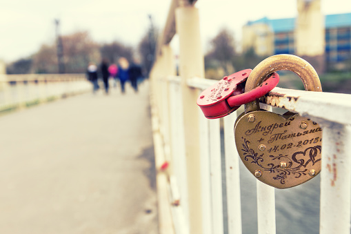 Two padlock on the bridge, there are people on the background