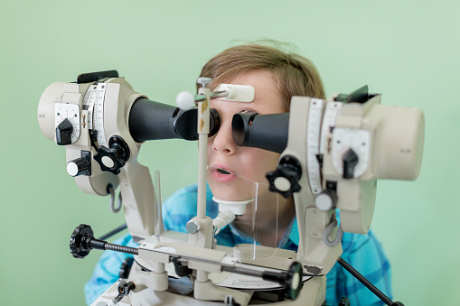 Boy undergoing eye exam on strabism medical equipment