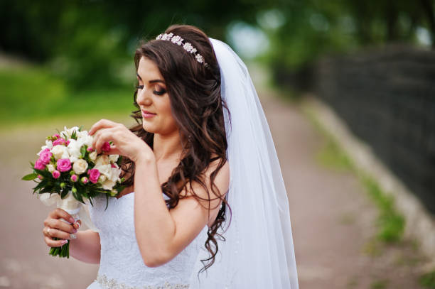 istock Charming brunette bride with bouquet at park. 658890830