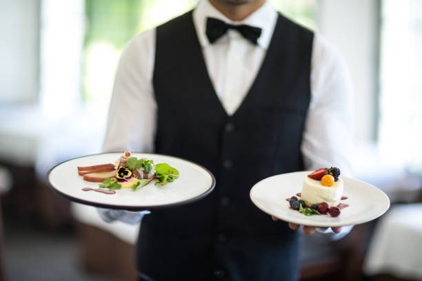 Waiter showing a dish Waiter showing a dish in a commercial kitchen serving dish stock pictures, royalty-free photos & images