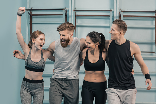 smiling sporty men and women in gym