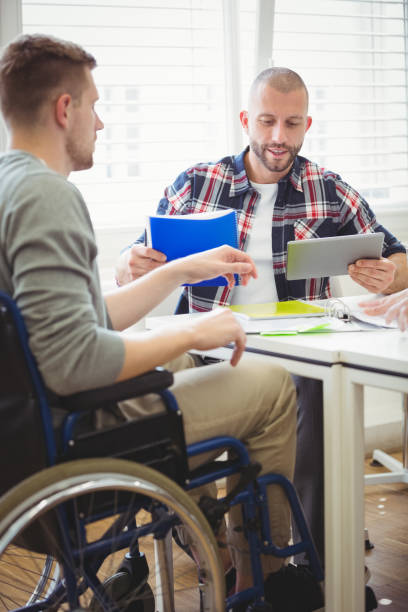 istock Businessman using digital tablet with handicap colleague 658902150