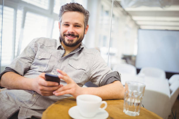 istock Smiling businessman using mobile phone in creative office 658902658