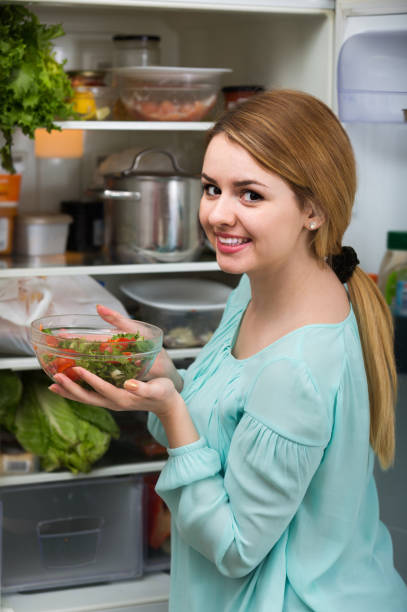 istock long-haired woman arranging space in fridge at home 658909876