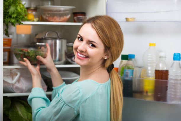 istock long-haired woman arranging space in fridge at home 658909890