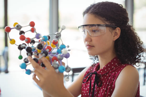 Attentive schoolgirl experimenting molecule model in laboratory Attentive schoolgirl experimenting molecule model in laboratory at school physics stock pictures, royalty-free photos & images